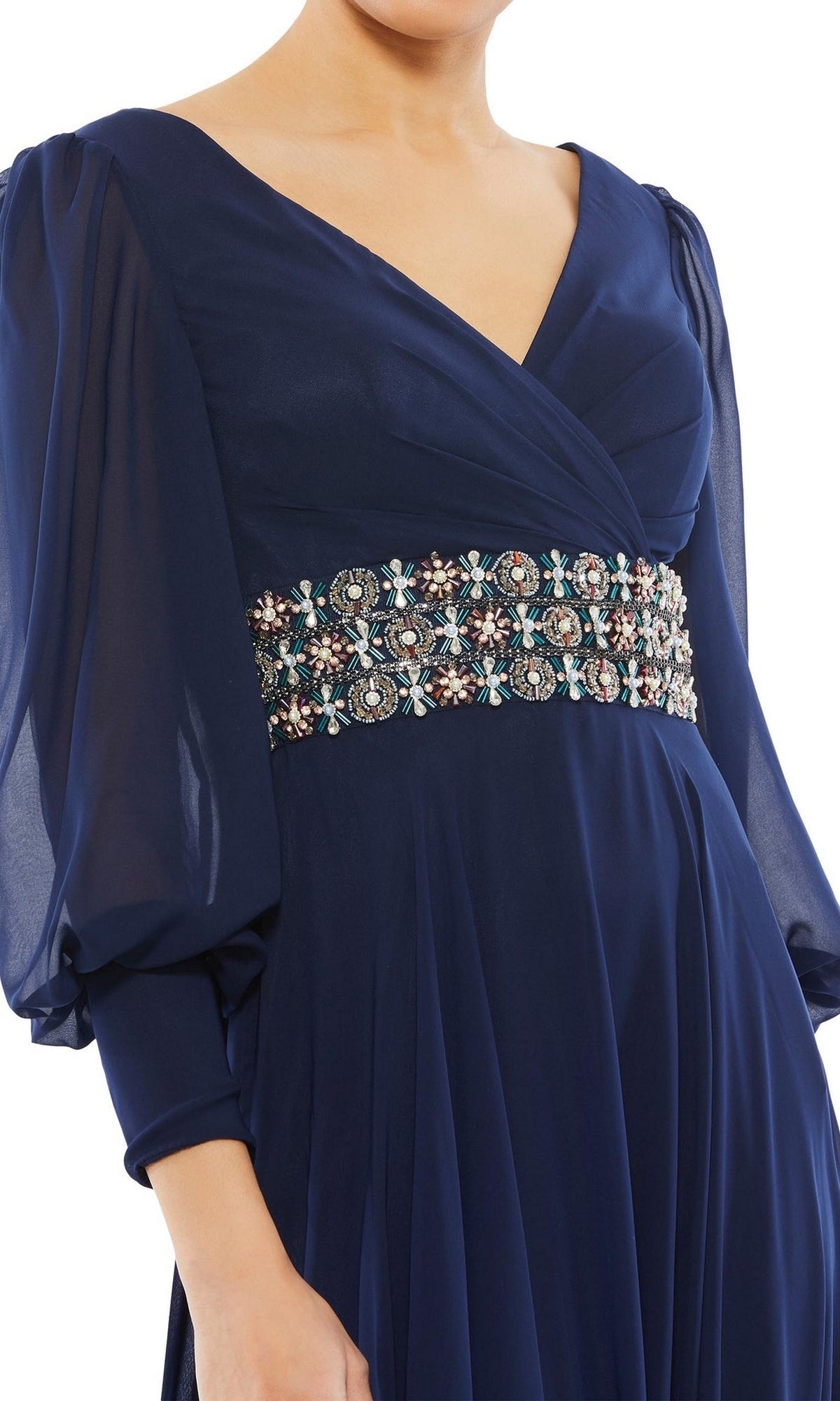 A woman in the Mac Duggal 79390 long formal dress, featuring navy blue sheer long sleeves and a multicolored beaded waistband—an elegant option for mother of the bride or any evening gown occasion.